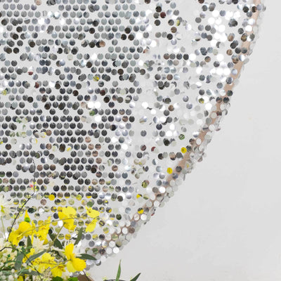 Shiny silver sequin backdrop with vibrant yellow flowers in the foreground.
