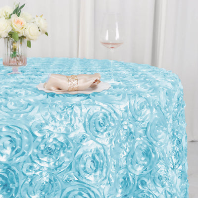 Light blue rose-patterned tablecloth with elegant napkin and wine glass on a table.