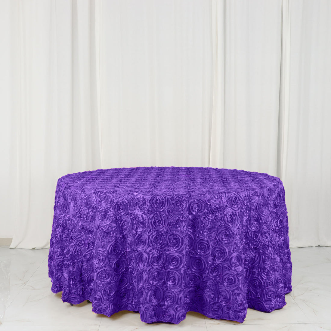 Purple rose-patterned tablecloth on a round table.