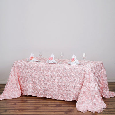 Pink rose tablecloth with elegant napkin folds and glassware set for dining.