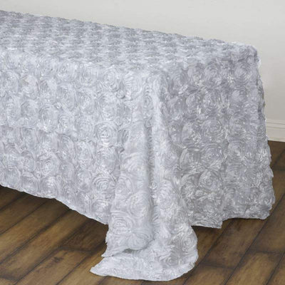 Silver rose-patterned tablecloth on a wooden surface.