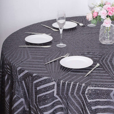 Round black and silver patterned tablecloth on a dining table with plates and glasses.