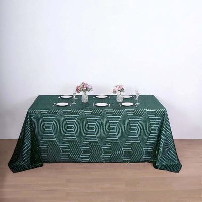 Green geometric patterned tablecloth on a wooden table with floral centerpieces.