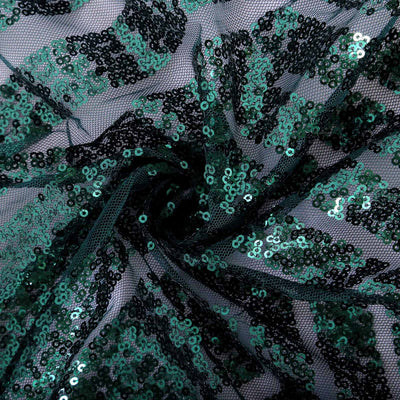 Black and green sequin fabric in a swirling pattern.