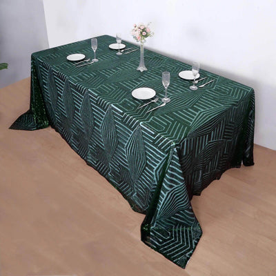 Elegant green geometric tablecloth draped over a dining table set for a meal.