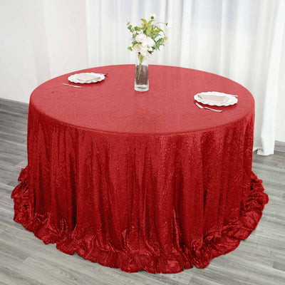 Red sequin tablecloth draped elegantly over a round table with a vase and plates.
