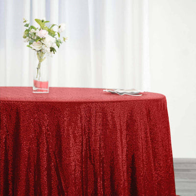 Red sequin tablecloth draped over a table with a vase of flowers.