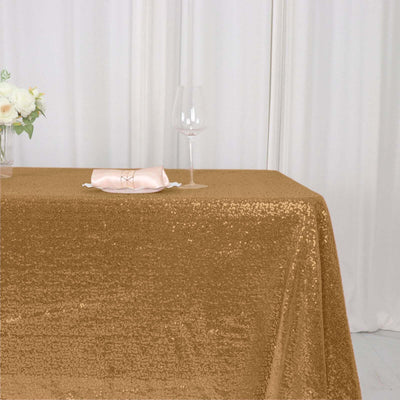 Gold sequin tablecloth draped on a table with glass and napkin