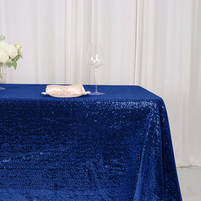 Blue sequin tablecloth draped on a table with a glass and napkin