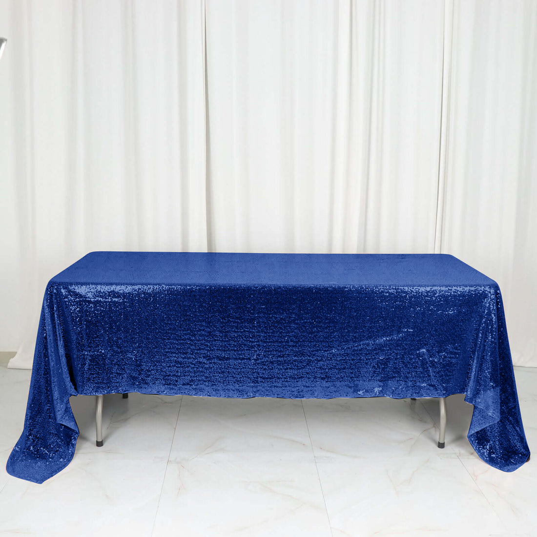 Shiny blue sequin tablecloth on a table against a white backdrop