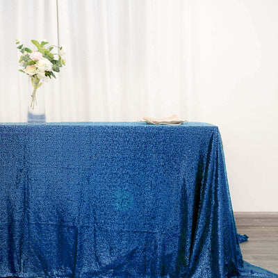 Blue sequined tablecloth with elegant floral arrangement and tableware.