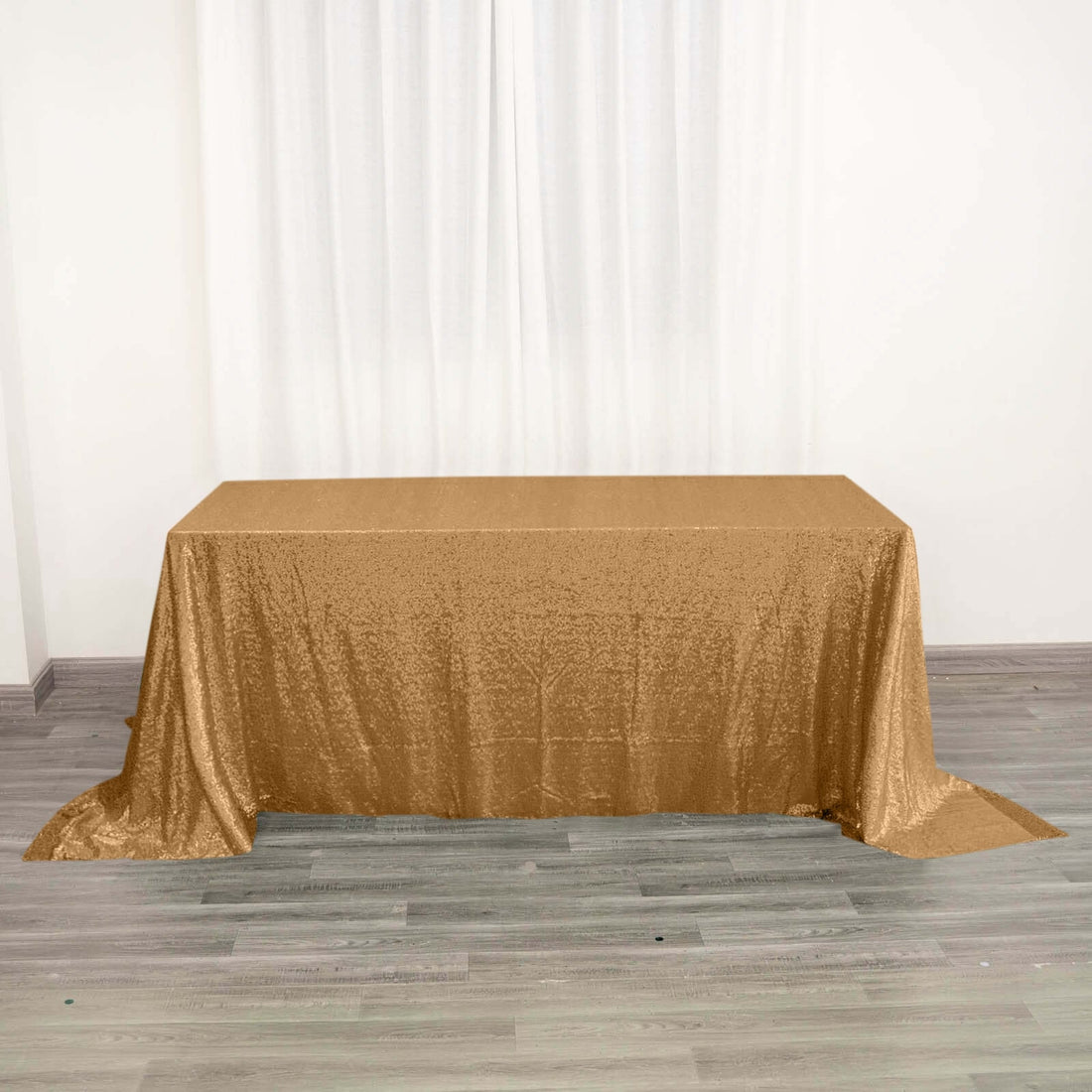 Gold sequin tablecloth on a plain table with a neutral backdrop