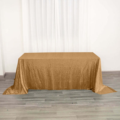 Gold sequin tablecloth on a plain table with a neutral backdrop