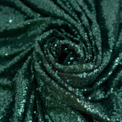 Green sequin fabric in a swirling pattern, showcasing its shiny texture. #whtbkgd