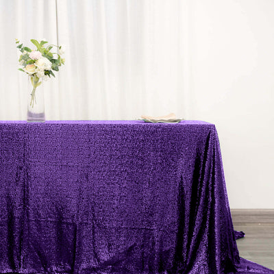 Purple sequin tablecloth draped elegantly on a table with flowers.