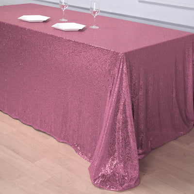 Pink sequin tablecloth draped over a table with wine glasses and plates.