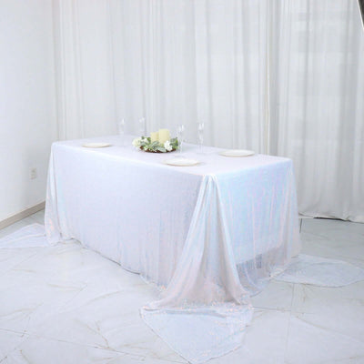 Elegant white table with shimmering tablecloth and floral centerpiece.