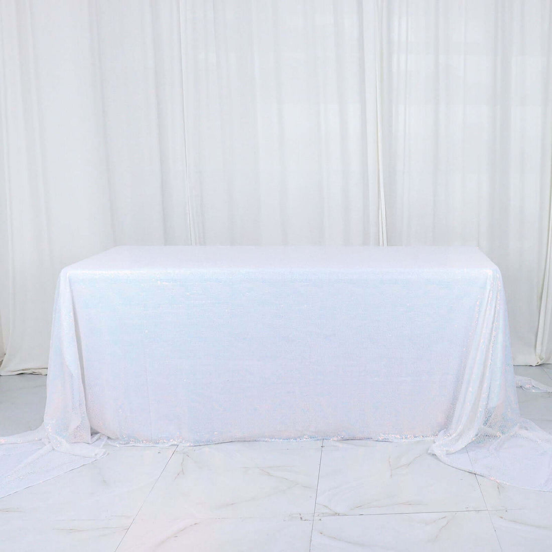 White sequin tablecloth draped over a table in a studio setting.