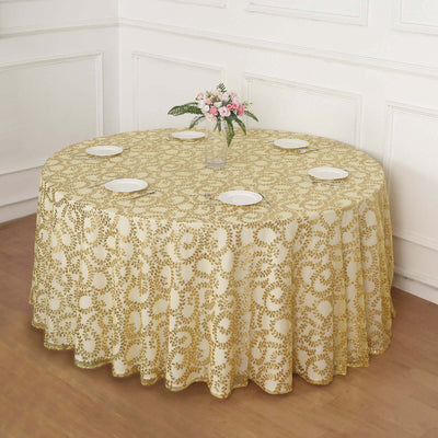 Round gold floral tablecloth draped over a table with plates and a vase of flowers.
