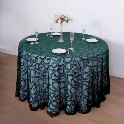 Round table with green patterned tablecloth, set for dining with plates and glasses.