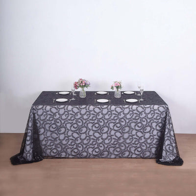 Elegant black lace tablecloth with floral pattern, set for dinner.