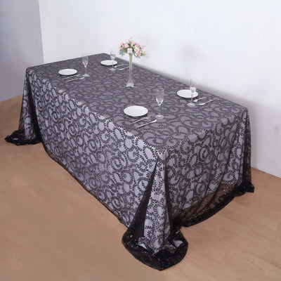 Elegant black and gray lace tablecloth on a dining table with plates and glasses.