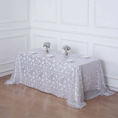 Elegant lace tablecloth with floral accents and dinnerware setup.