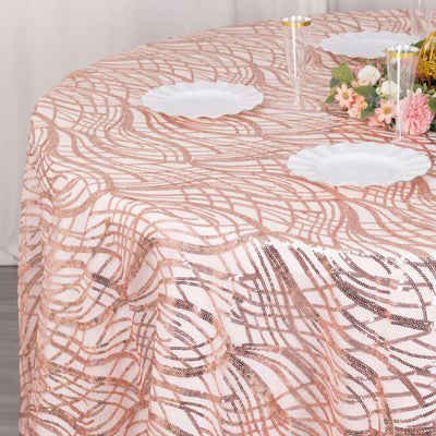 Rose gold sequin tablecloth on a round table with decorative plates and flowers.