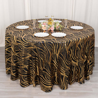 Elegant black and gold swirl tablecloth on a round table with decorative plates and centerpiece.