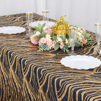 Elegant black and gold tablecloth with floral centerpiece and glassware.