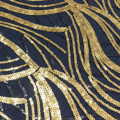 Gold sequin fabric with intricate patterns on a dark background.
