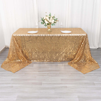 Gold sequin tablecloth draped over a table with floral centerpiece and plates.