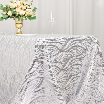 Elegant silver and white tablecloth with intricate patterns on a dining table.