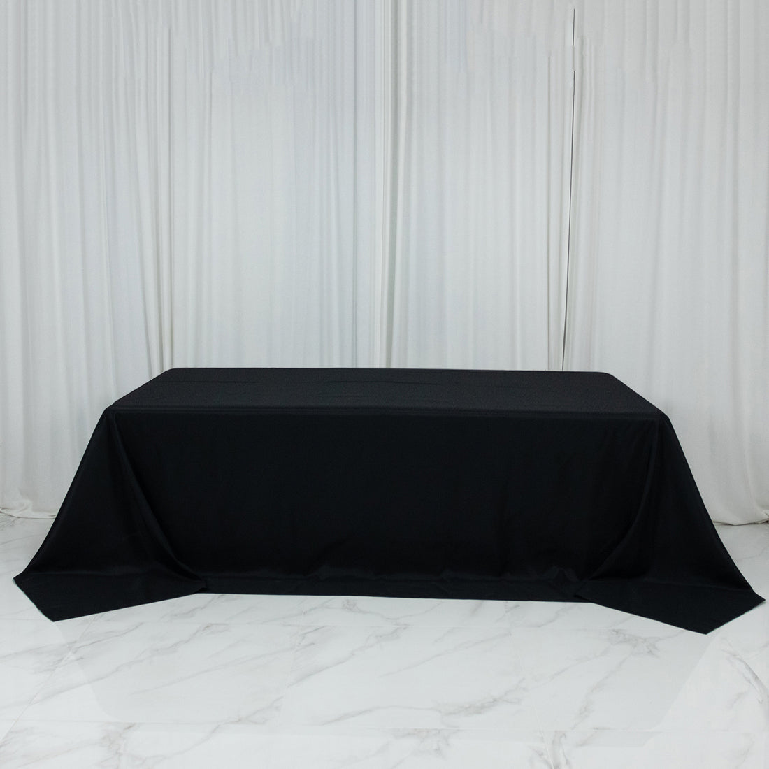 Black tablecloth draped over a rectangular table in a studio setting.