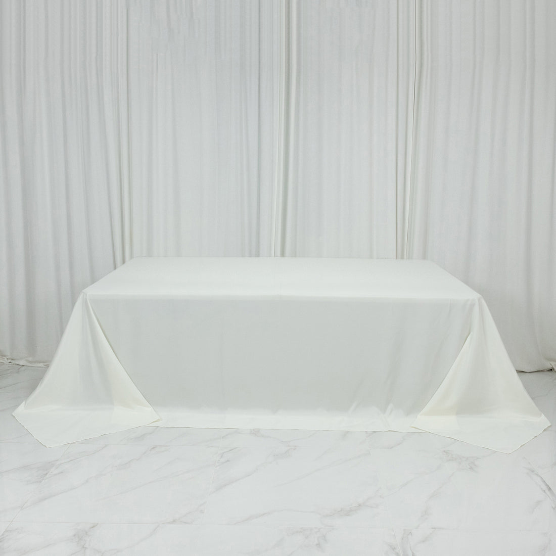 White tablecloth draped elegantly over a table against a plain backdrop.