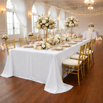 Elegant wedding reception setup with floral centerpieces and gold chairs.