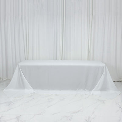 White tablecloth draped over a table on a plain backdrop.