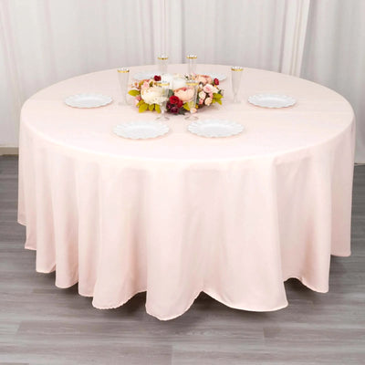Round pink tablecloth draped over a table with floral centerpiece and plates.