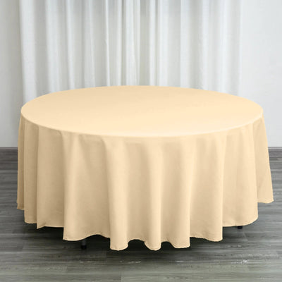 Round beige tablecloth on a table in a bright setting.