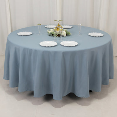 Round blue tablecloth with white plates and decorative centerpiece.