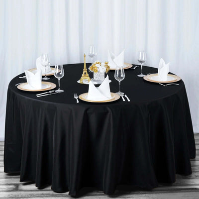 Elegant round dining table set with black tablecloth and elegant tableware.