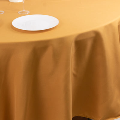 Round mustard tablecloth draped over a table with a white plate.