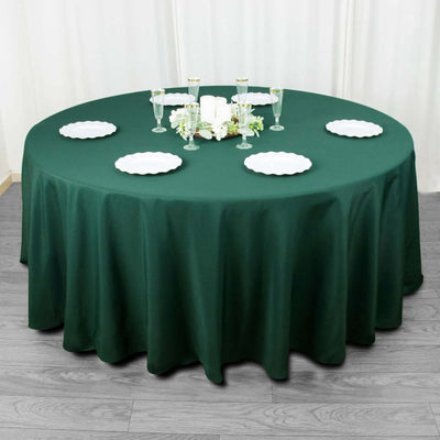 Round green tablecloth draping a table set with plates and glasses.