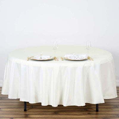 Elegant round table set with white tablecloth and fine dining utensils.