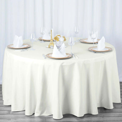 Elegant round table set with white tablecloth, plates, and glasses.