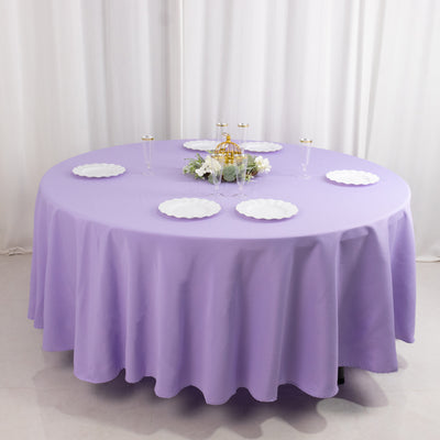 Round lavender tablecloth draped on a table with white plates arranged.