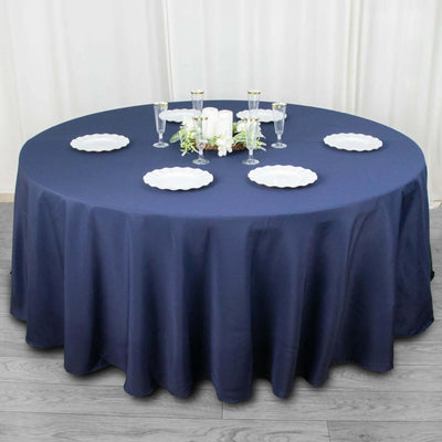 Round navy tablecloth with white plates and candles arranged elegantly.