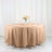 Round beige tablecloth draped over a table with plates and floral centerpiece.