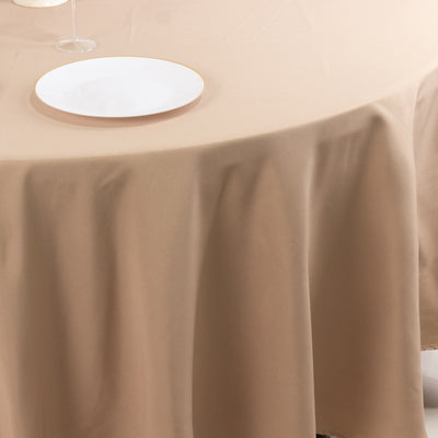 Beige tablecloth draped elegantly over a dining table with a white plate on top.
