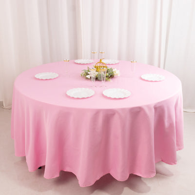 Pink tablecloth draped over a round table with decorative plates and centerpiece.